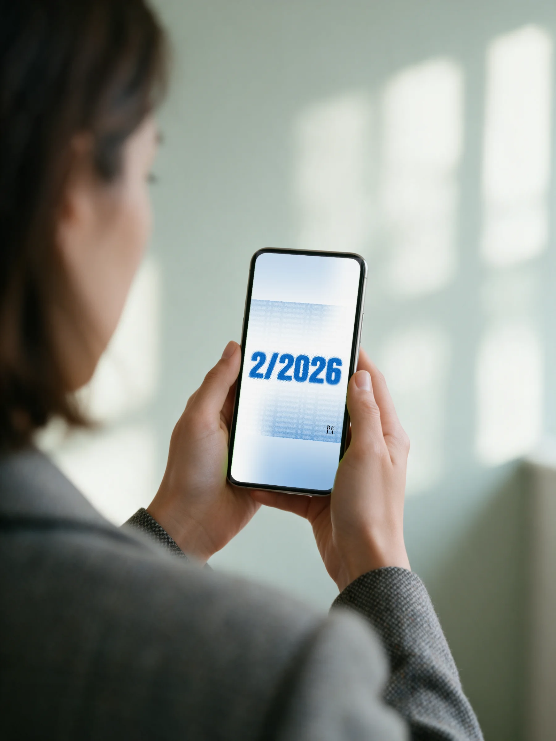 Mockup: person seen from behind, phone showing 2/2026