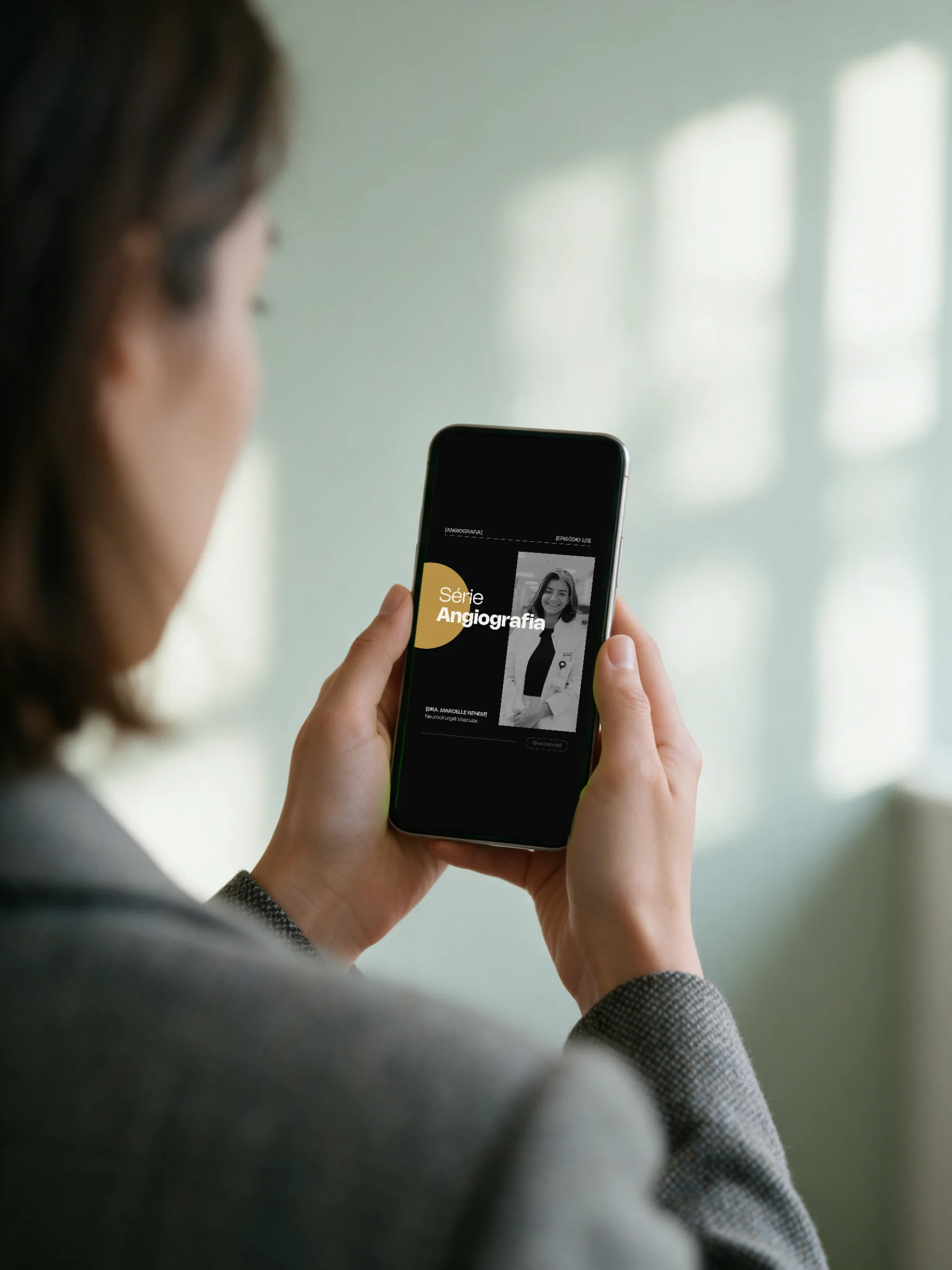 Mockup: person seen from behind, phone showing the Angiografia series cover